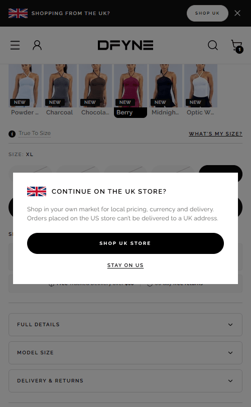 The US store on a phone with a card over it reading 'Continue on the UK store?' — 'Shop in your own market for local pricing, currency and delivery. Orders placed on the US store can't be delivered to a UK address.' — above a 'Shop UK store' button and a 'Stay on US' link. A bar pinned to the top of the page asks the same thing.